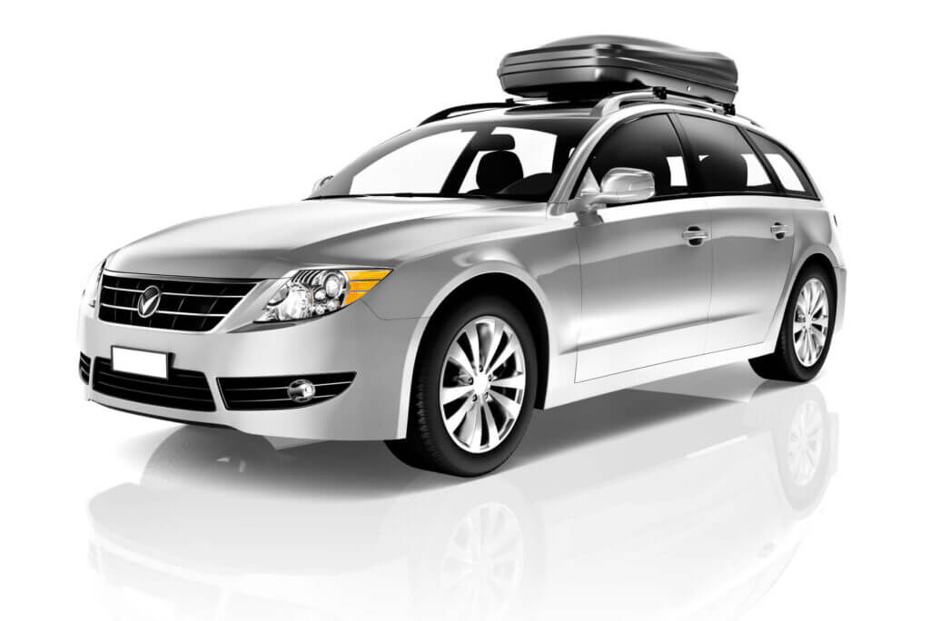 A silver station wagon with a roof box is parked on a reflective white surface, showcasing sleek design and modern features.