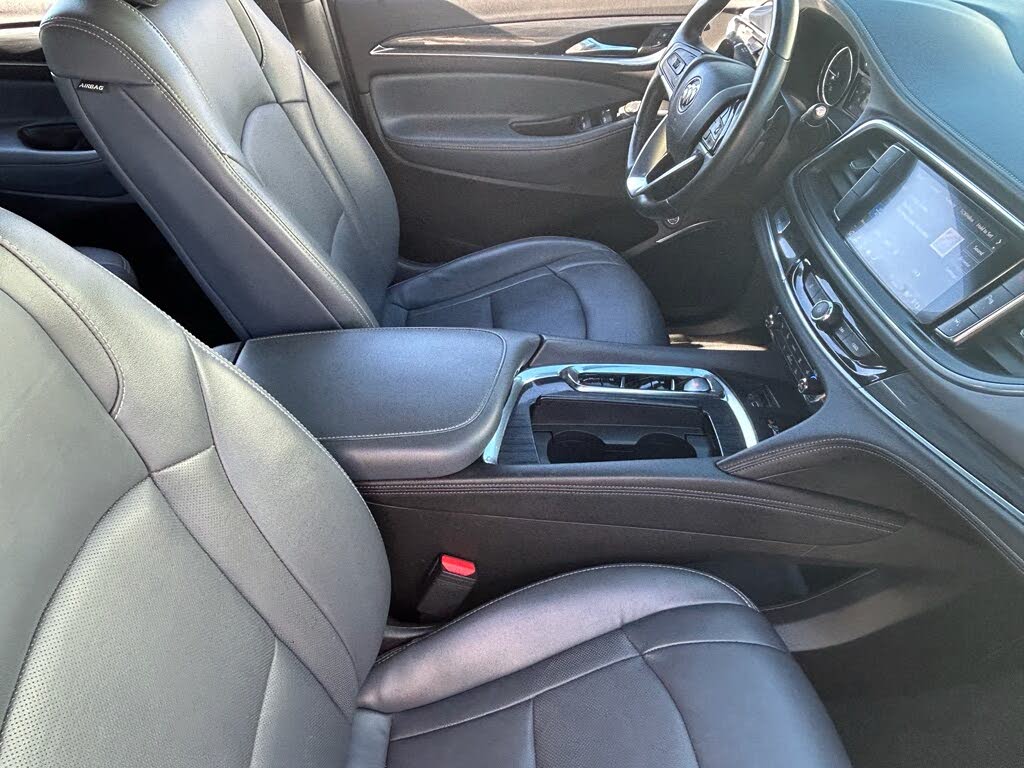 11 Front interior of a car with black leather seats, a center console, and a touchscreen dashboard.