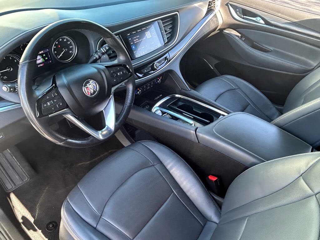 16 Interior of a car with black leather seats, a steering wheel, and a center console with a touchscreen display.