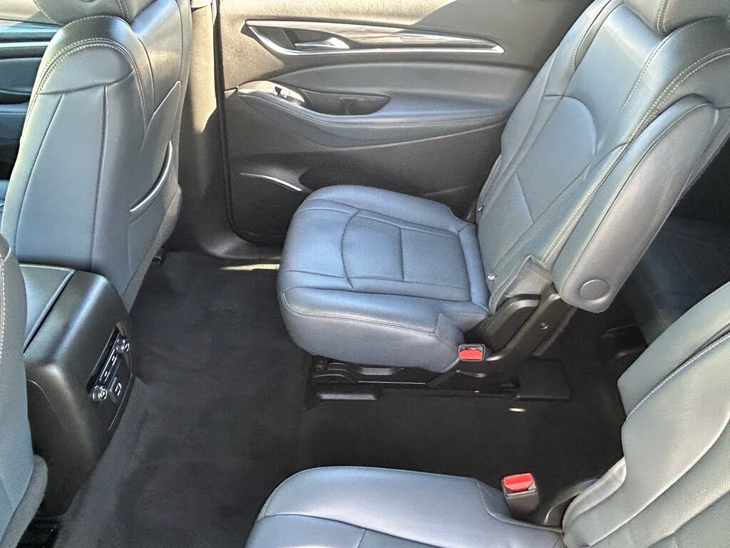 17 Gray leather captain chairs in the rear passenger area of a car with a black carpet.