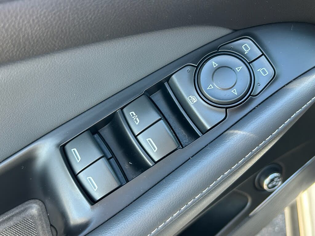 19 Close-up of a car door panel with window control buttons and a circular mirror adjustment knob.