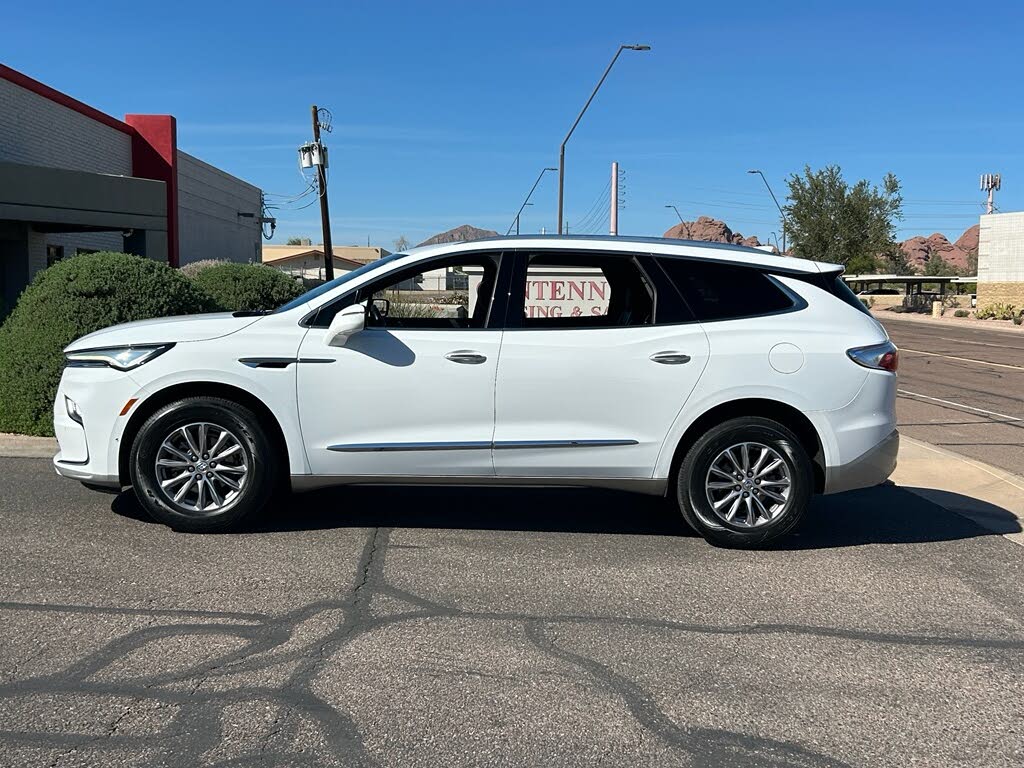 2 White SUV with roof rails parked in a parking lot, with a sign in the rear side window.