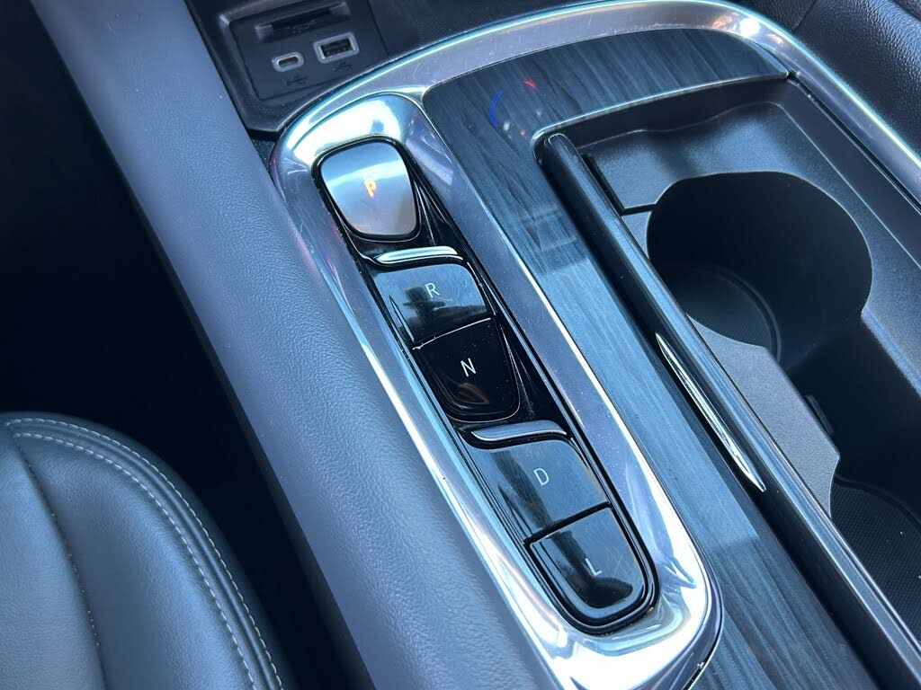 22 Close-up of a car's center console with a glossy chrome gear selector and a nearby cup holder.