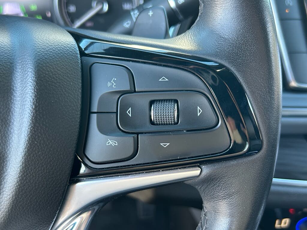 23 Close-up of a car steering wheel control cluster with a central scroll wheel and surrounding directional buttons.