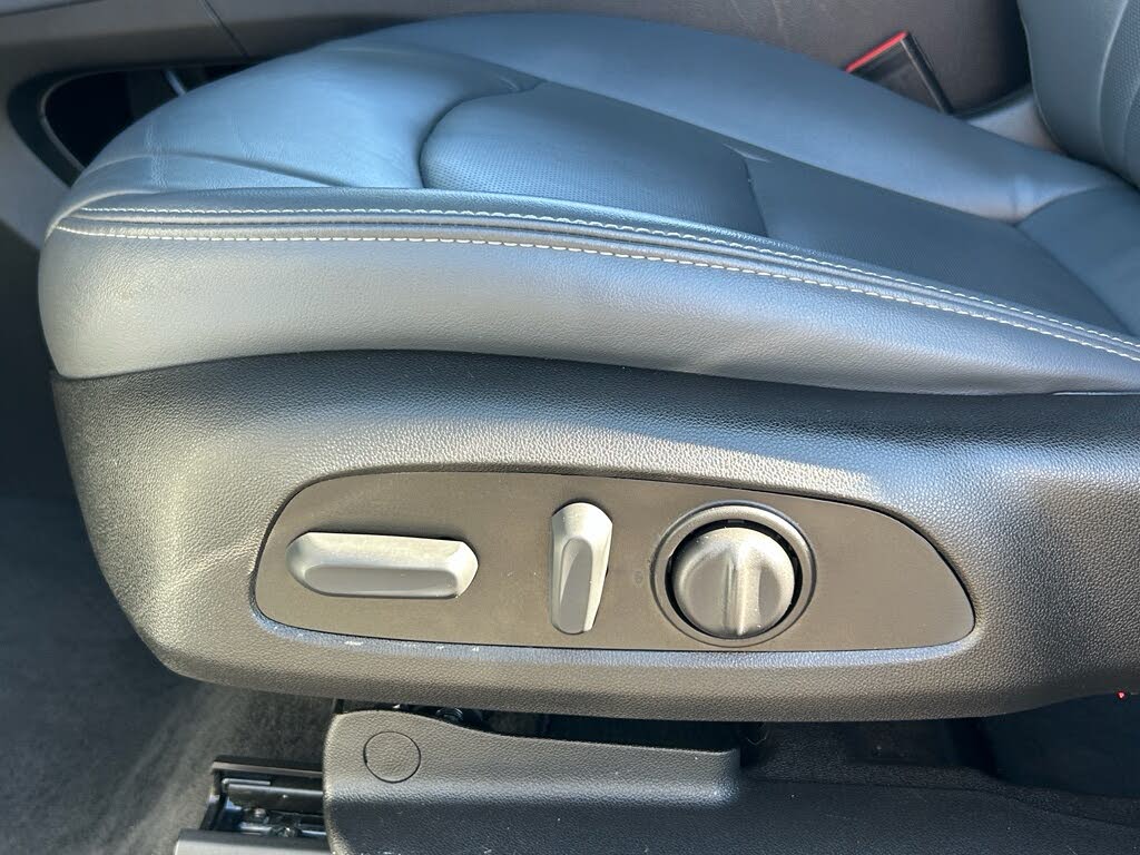 31 Blue leather car seat with side-mounted power-adjustment controls, including a horizontal switch, a vertical switch, and a round dial.