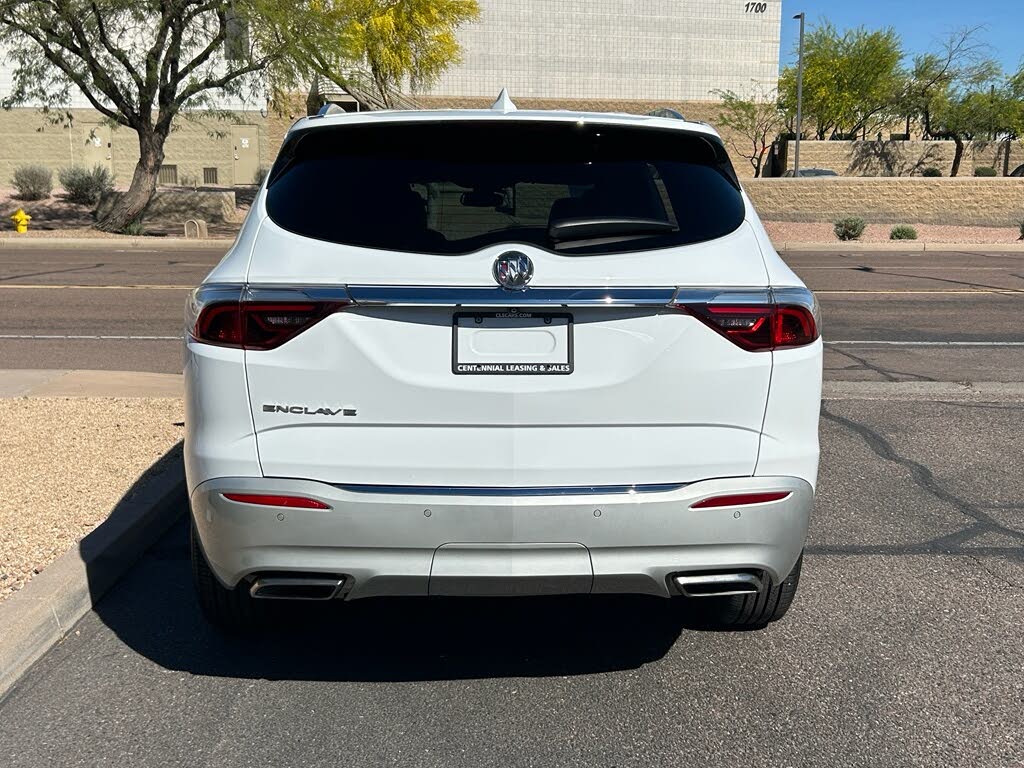 4 Rear view of a white Buick Enclave SUV parked on a paved street with desert landscaping in the background.